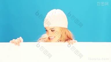笑着快乐的金发女人拿着一个空白的白色横幅，穿着冬天